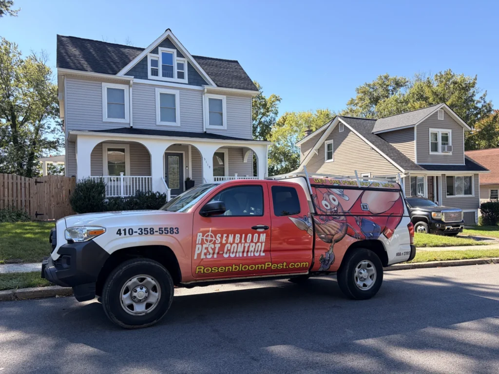 Rosenbloom Pest Control truck parked in front of a two-story gray home with a covered front porch